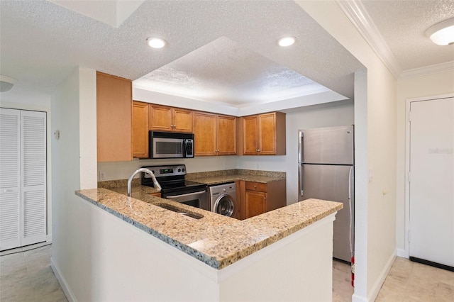 kitchen with light stone countertops, washer / dryer, kitchen peninsula, and appliances with stainless steel finishes