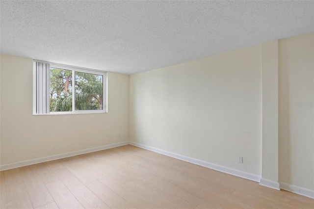 spare room with a textured ceiling and light hardwood / wood-style floors