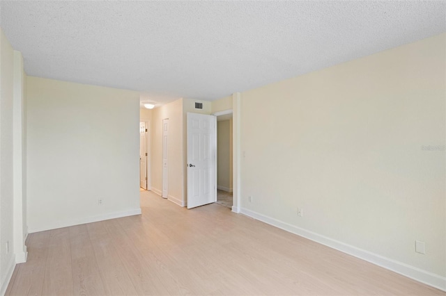 unfurnished room with light hardwood / wood-style flooring and a textured ceiling