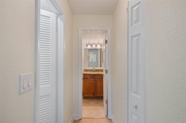 hallway featuring a textured ceiling and sink