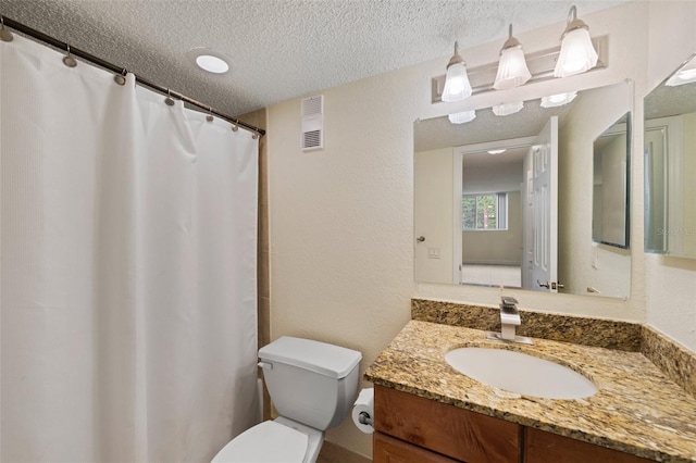 bathroom with vanity, a textured ceiling, and toilet