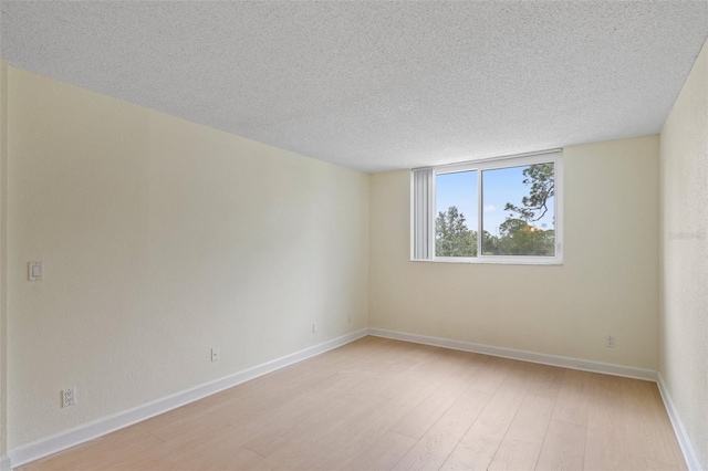 spare room featuring light hardwood / wood-style floors and a textured ceiling