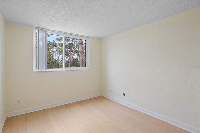 spare room with a textured ceiling and light hardwood / wood-style floors