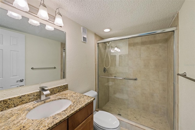 bathroom with a textured ceiling, vanity, an enclosed shower, and toilet