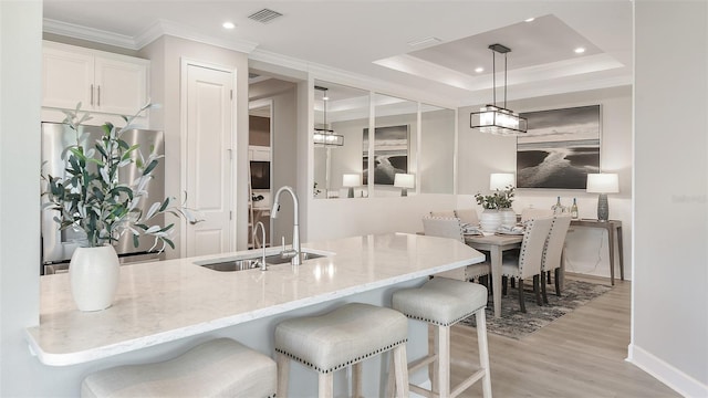 kitchen featuring stainless steel refrigerator, light stone countertops, sink, decorative light fixtures, and white cabinets