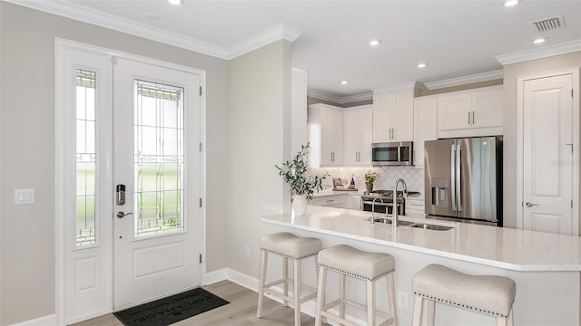 kitchen with kitchen peninsula, a kitchen breakfast bar, white cabinetry, and stainless steel appliances