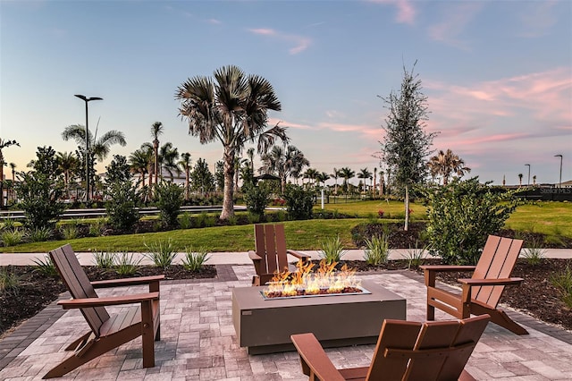 patio terrace at dusk with a fire pit and a lawn