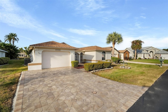 view of front of home with central AC unit, a garage, and a front lawn