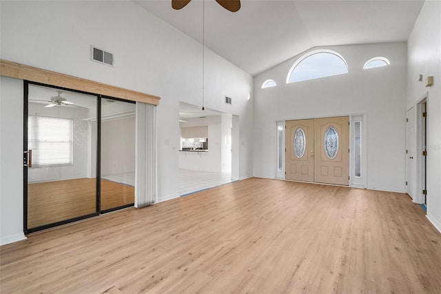 foyer with light wood-type flooring and high vaulted ceiling