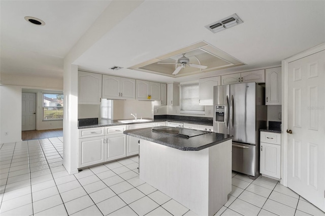 kitchen featuring stainless steel fridge, black electric stovetop, ceiling fan, sink, and white cabinets