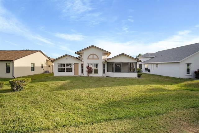 rear view of house featuring a sunroom and a lawn