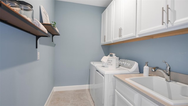 clothes washing area featuring cabinets, light tile patterned floors, washing machine and dryer, and sink