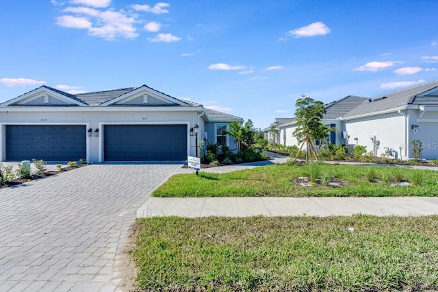 ranch-style home with a garage, a front lawn, decorative driveway, and stucco siding