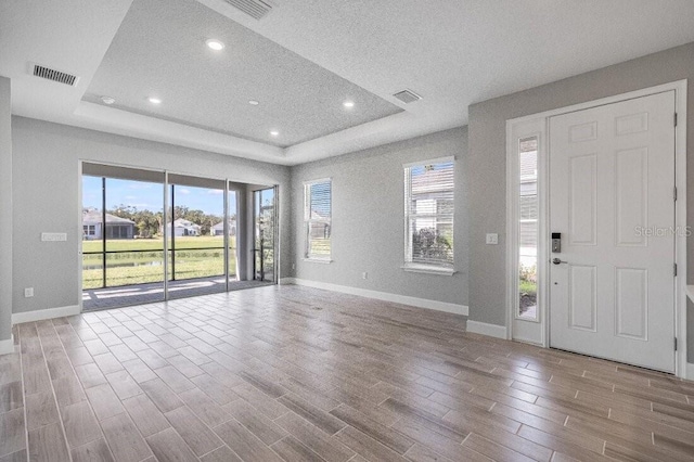 entryway featuring a healthy amount of sunlight, a tray ceiling, and wood finished floors