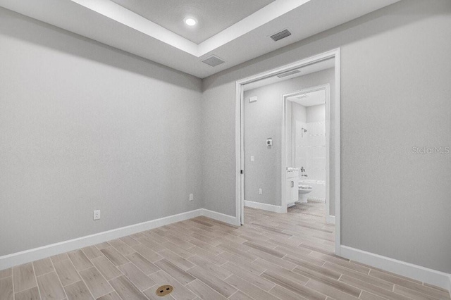 empty room with baseboards, visible vents, and wood finish floors