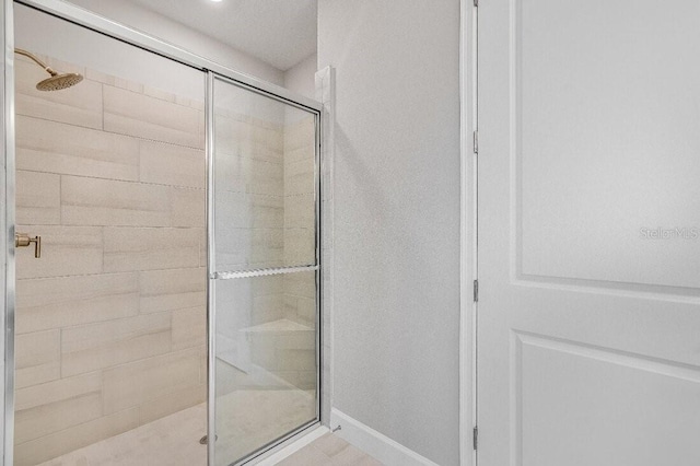 bathroom with a stall shower and baseboards