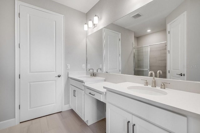 bathroom featuring a stall shower, visible vents, a sink, and double vanity