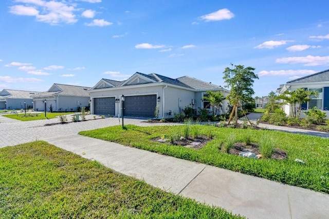 view of front of property featuring a front yard, decorative driveway, an attached garage, and stucco siding