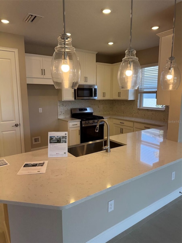 kitchen with pendant lighting, stainless steel appliances, and white cabinets