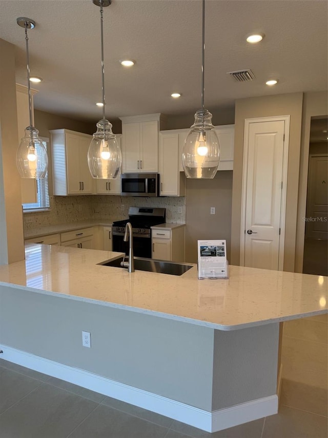 kitchen featuring hanging light fixtures, stainless steel appliances, and white cabinets