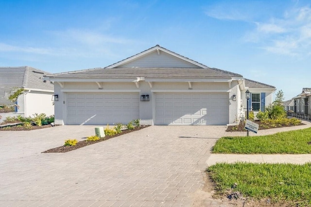 ranch-style home with an attached garage, decorative driveway, and stucco siding