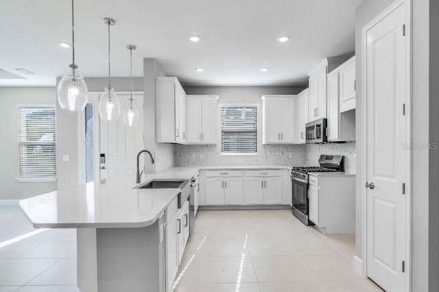 kitchen with light tile patterned floors, stainless steel appliances, a peninsula, a sink, and decorative backsplash