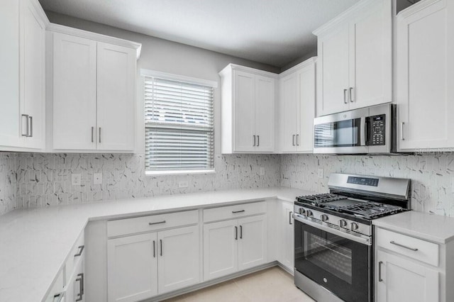 kitchen with appliances with stainless steel finishes, light countertops, white cabinetry, and decorative backsplash