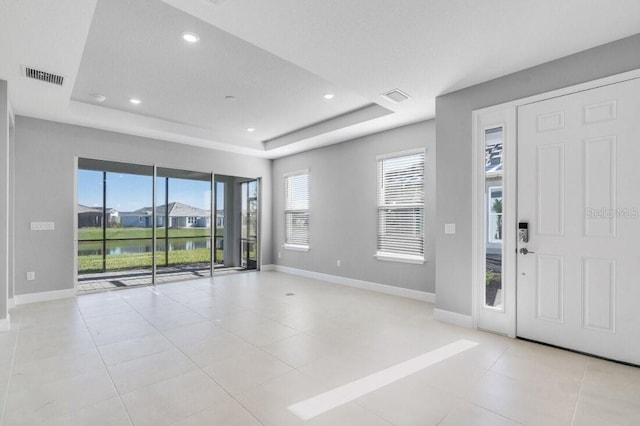 foyer with baseboards, visible vents, and a raised ceiling