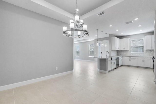 kitchen with tasteful backsplash, open floor plan, a peninsula, light countertops, and white cabinetry