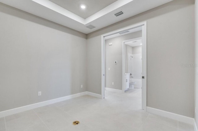 spare room with recessed lighting, a tray ceiling, visible vents, and baseboards