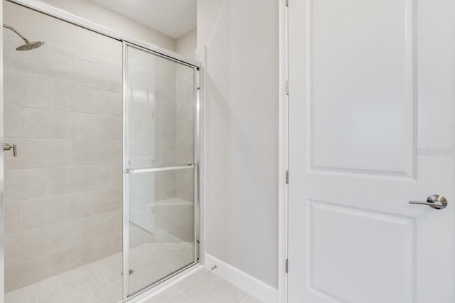 bathroom featuring a shower stall, baseboards, and tile patterned flooring