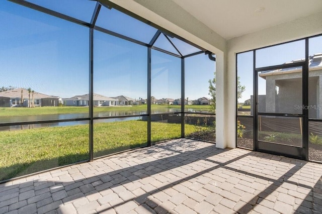 unfurnished sunroom with a residential view and a water view