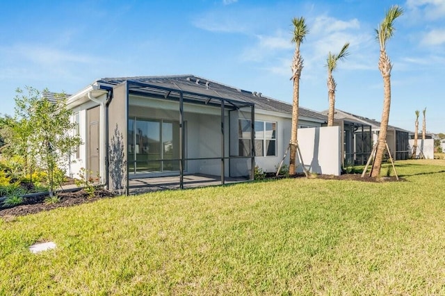 rear view of property featuring a patio, a lawn, a lanai, and stucco siding