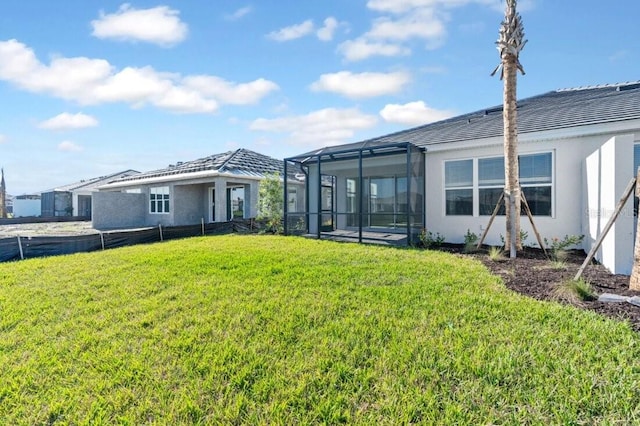 back of property with glass enclosure, stucco siding, and a yard