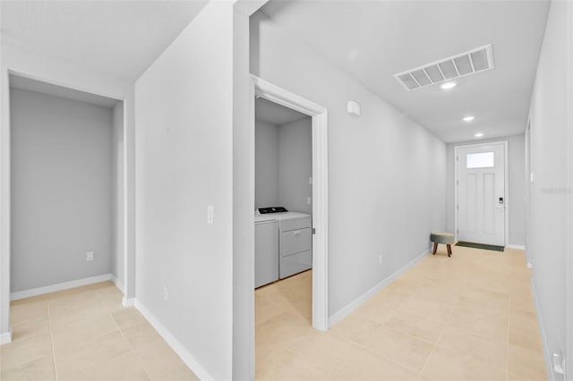 corridor with independent washer and dryer and light tile patterned floors