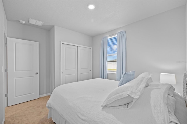 carpeted bedroom with a textured ceiling and a closet