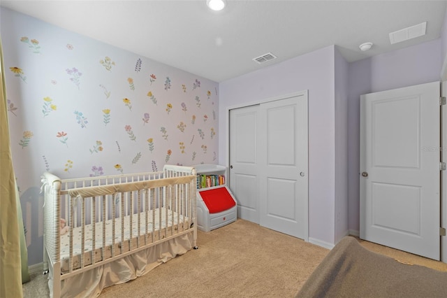 carpeted bedroom featuring a closet and a nursery area