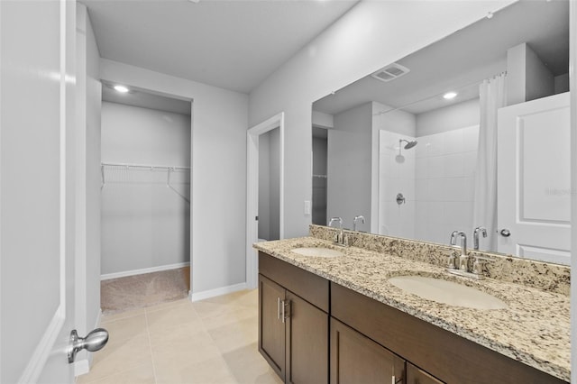 bathroom with tile patterned flooring, a tile shower, and vanity