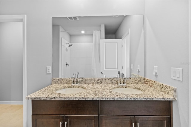 bathroom featuring tile patterned flooring, a tile shower, and vanity