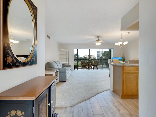 living room featuring a textured ceiling, ceiling fan with notable chandelier, and light colored carpet