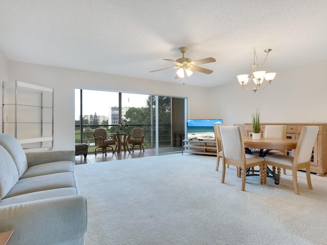 carpeted dining room with a textured ceiling and ceiling fan with notable chandelier