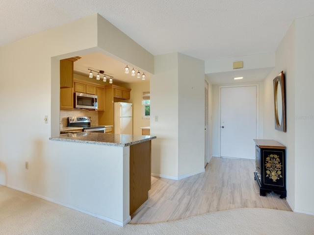 kitchen with a textured ceiling, kitchen peninsula, light wood-type flooring, and stainless steel appliances