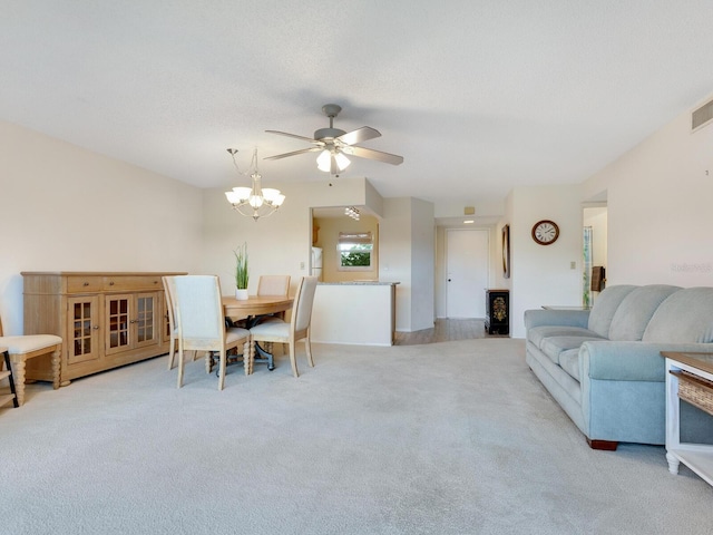 carpeted living room with ceiling fan with notable chandelier