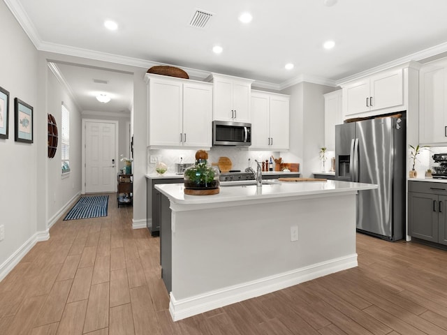 kitchen with white cabinets, appliances with stainless steel finishes, and a center island with sink