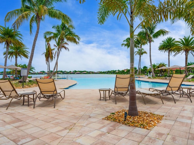 view of swimming pool featuring a water view and a patio