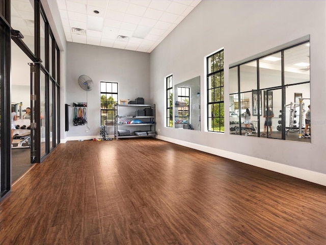 interior space featuring hardwood / wood-style floors, a paneled ceiling, a towering ceiling, and a wealth of natural light