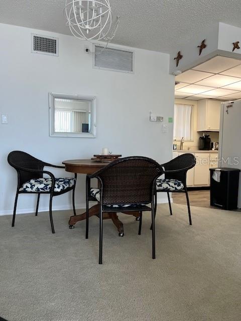 dining room featuring light carpet and a notable chandelier