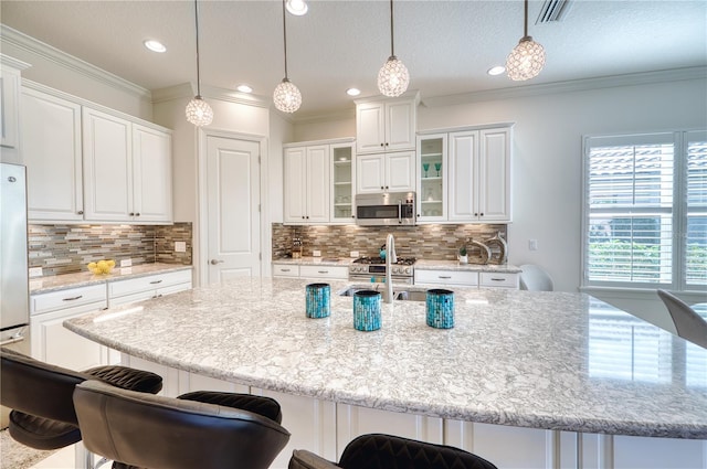 kitchen featuring tasteful backsplash, stainless steel appliances, pendant lighting, white cabinets, and a large island