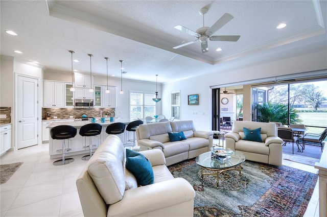 living room featuring ceiling fan, a raised ceiling, crown molding, a textured ceiling, and light tile patterned flooring