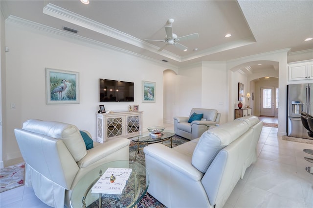 tiled living room with a textured ceiling, ceiling fan, crown molding, and a tray ceiling